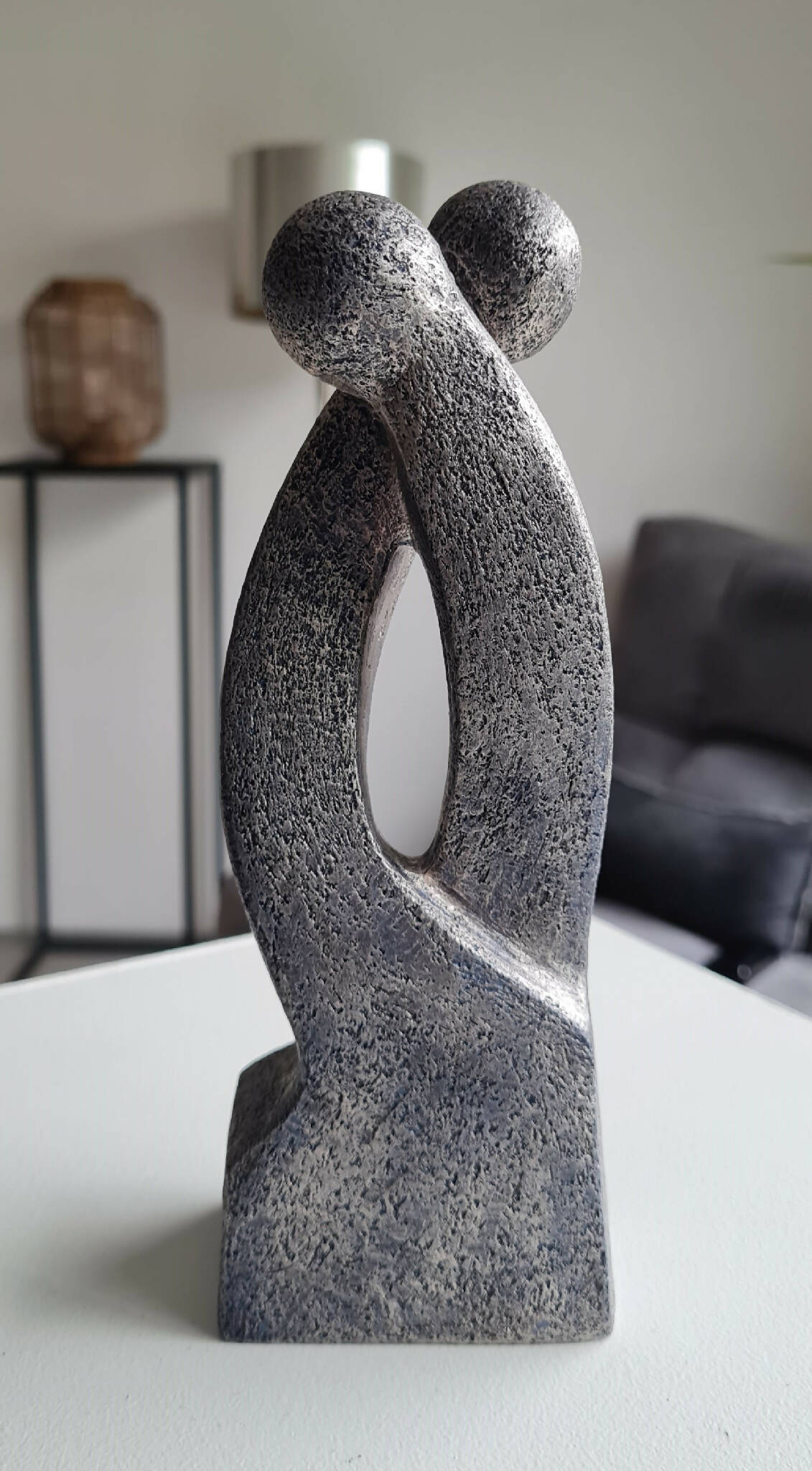 Sculpture en argile grise, silhouette en double courbe avec ouverture ovale et base droite.