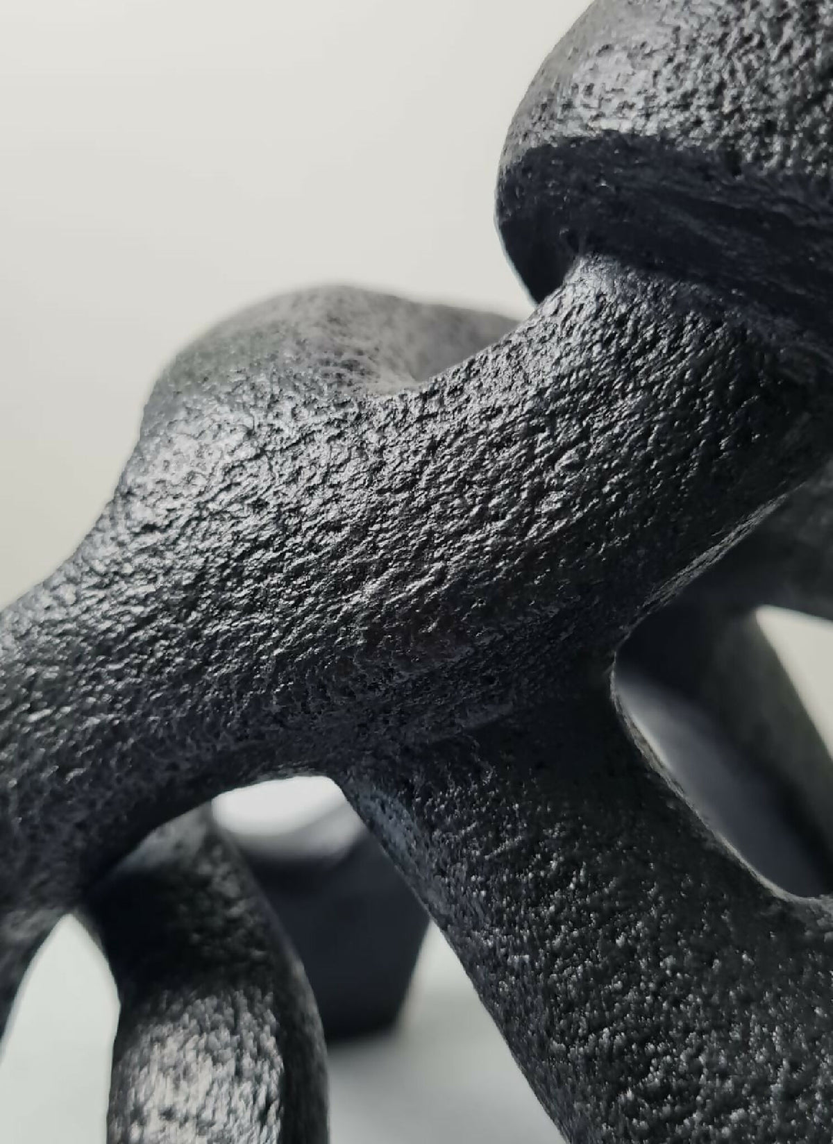 Détail de sculpture sombre à texture granuleuse, courbes avec ouvertures