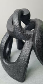 Sculpture abstraite contemporaine sombre, socle stable et volumes creusés