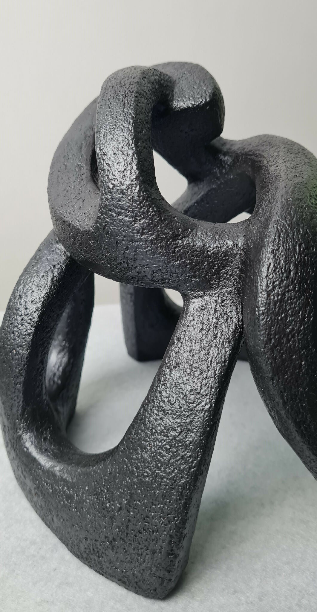 Sculpture abstraite contemporaine sombre, socle stable et volumes creusés