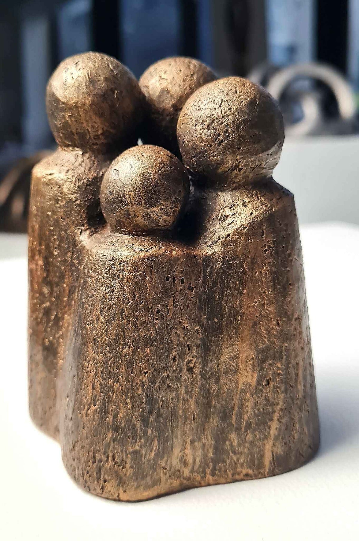 Sculpture contemporaine en bronze patiné, quatre têtes arrondies, vue de face.
