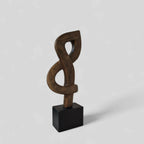 Sculpture abstraite en argile brun foncé, nœud entrelacé, sur socle noir.