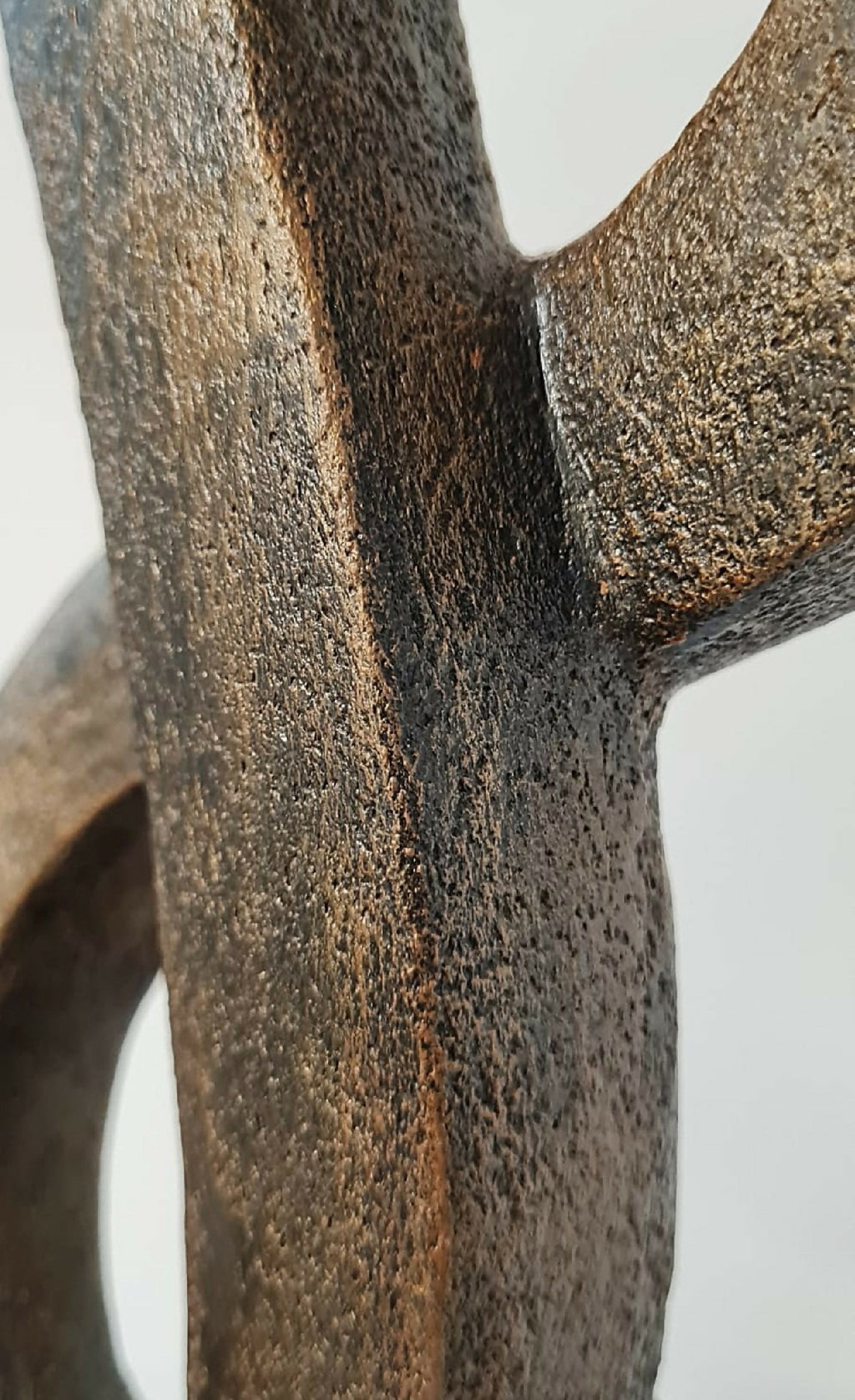 Pièce d’argile texturée brun, surface granuleuse, détail de forme entrelacée.