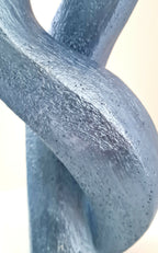 Détail de sculpture couple abstrait : silhouettes en métal bleu texturé, vue rapprochée.