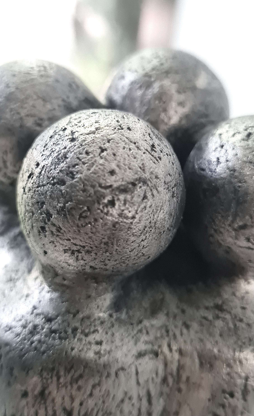 Détail d’une sculpture : trois boules texturées, figure centrale au premier plan