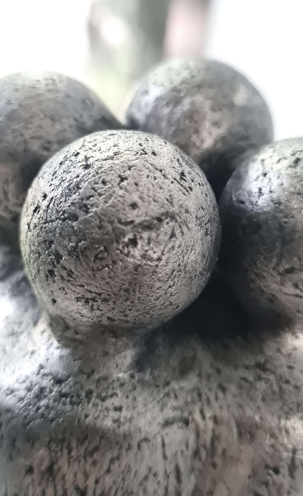Détail d’une sculpture : trois boules texturées, figure centrale au premier plan