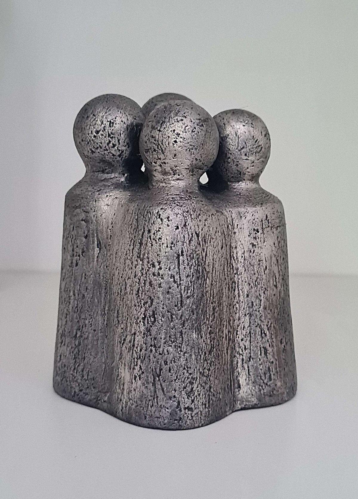 Sculpture contemporaine en gris foncé, trois personnages ronds sur une base