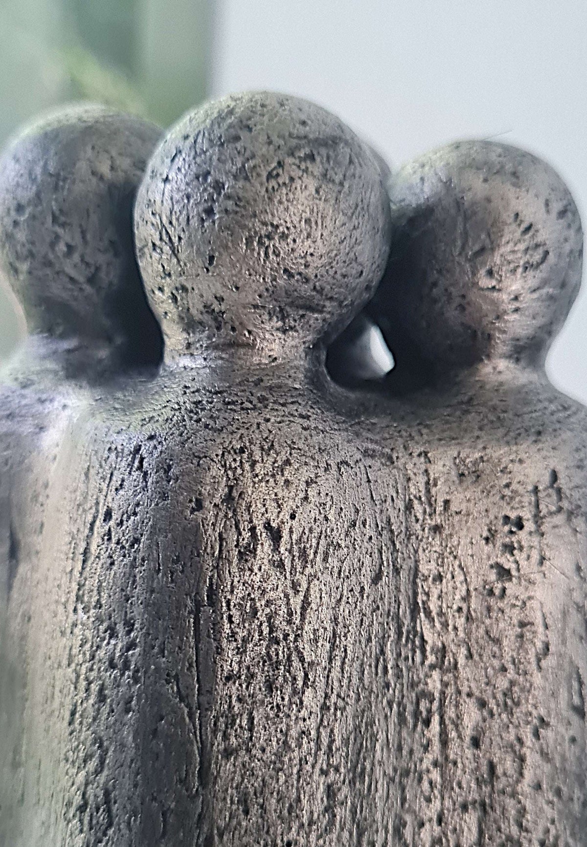 Vue rapprochée de la sculpture : textures granuleuses et trois têtes rondes