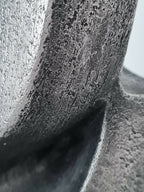 Détail de sculpture : surface métallique texturée gris foncé avec reliefs