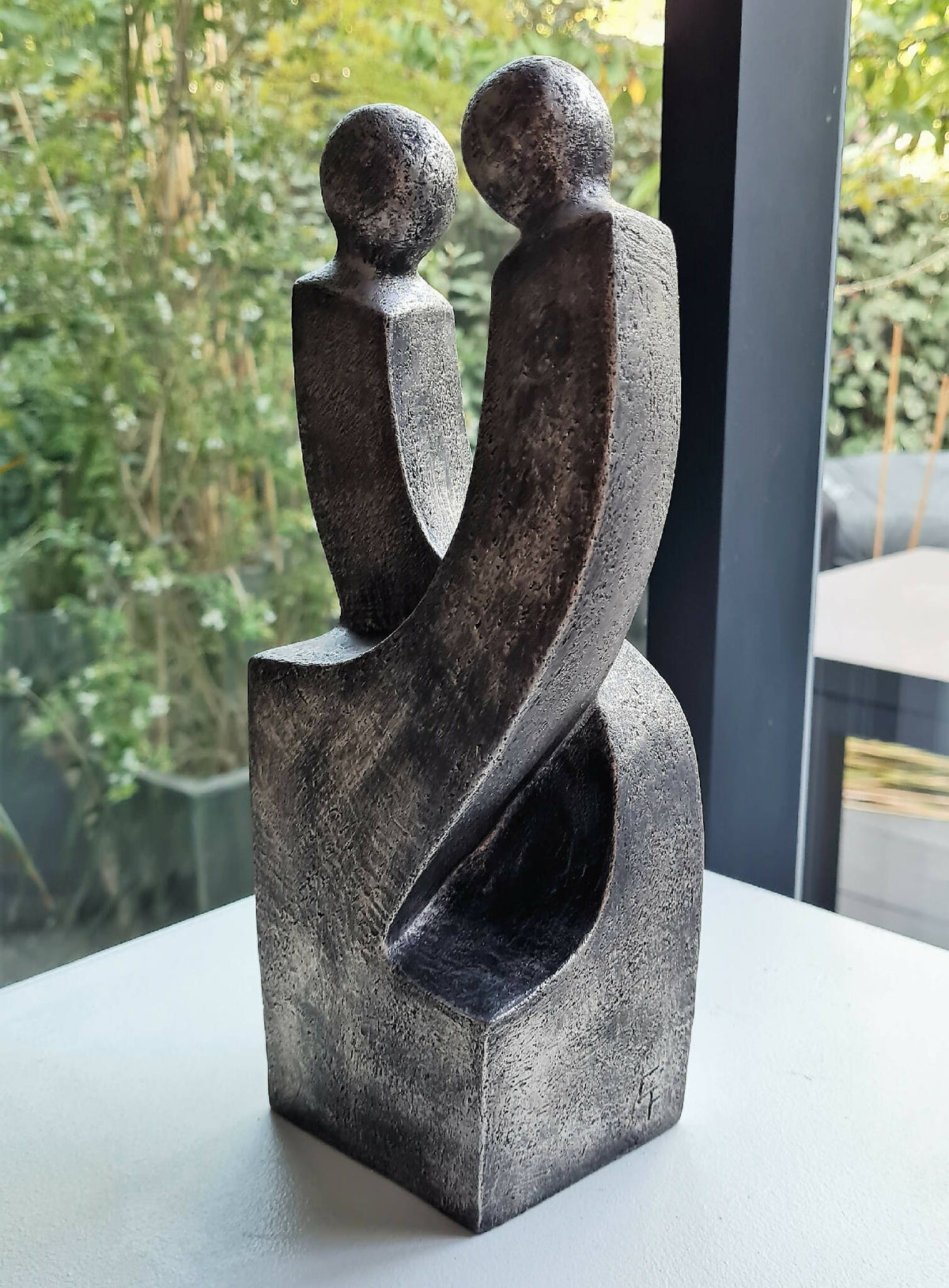 Sculpture de couple en métal gris foncé patiné, silhouettes enlacées sur socle
