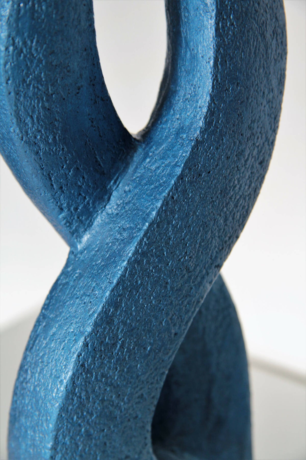 Détail de sculpture abstraite bleue avec surface texturée et ouverture en U.
