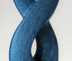 Gros plan sur sculpture bleue texturée, courbe en X avec ouverture sombre.