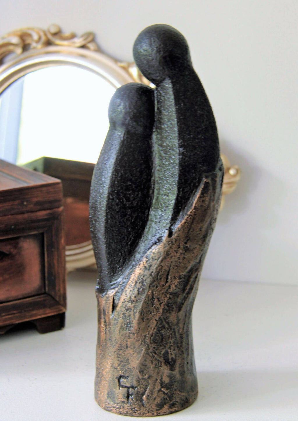 Sculpture couple sur socle, figurine noire patinée avec zones dorées, vue en perspective.
