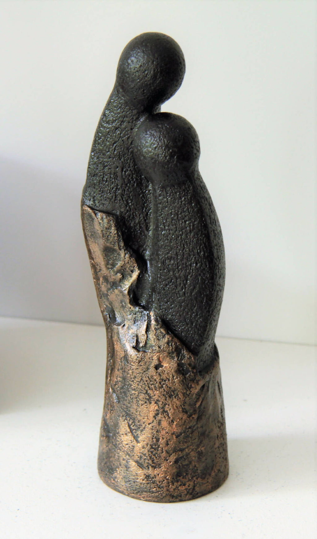 Sculpture couple en figurine : vue arrière, silhouettes noires et dorées, socle arrondi.