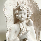 Sculpture en relief femme blanche, oiseau sur la tête, mains croisées, base noire