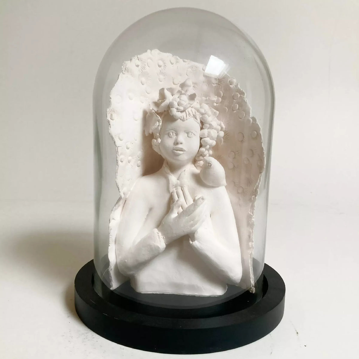 Sculpture en relief femme blanche sous cloche transparente, oiseau sur la tête, base noire