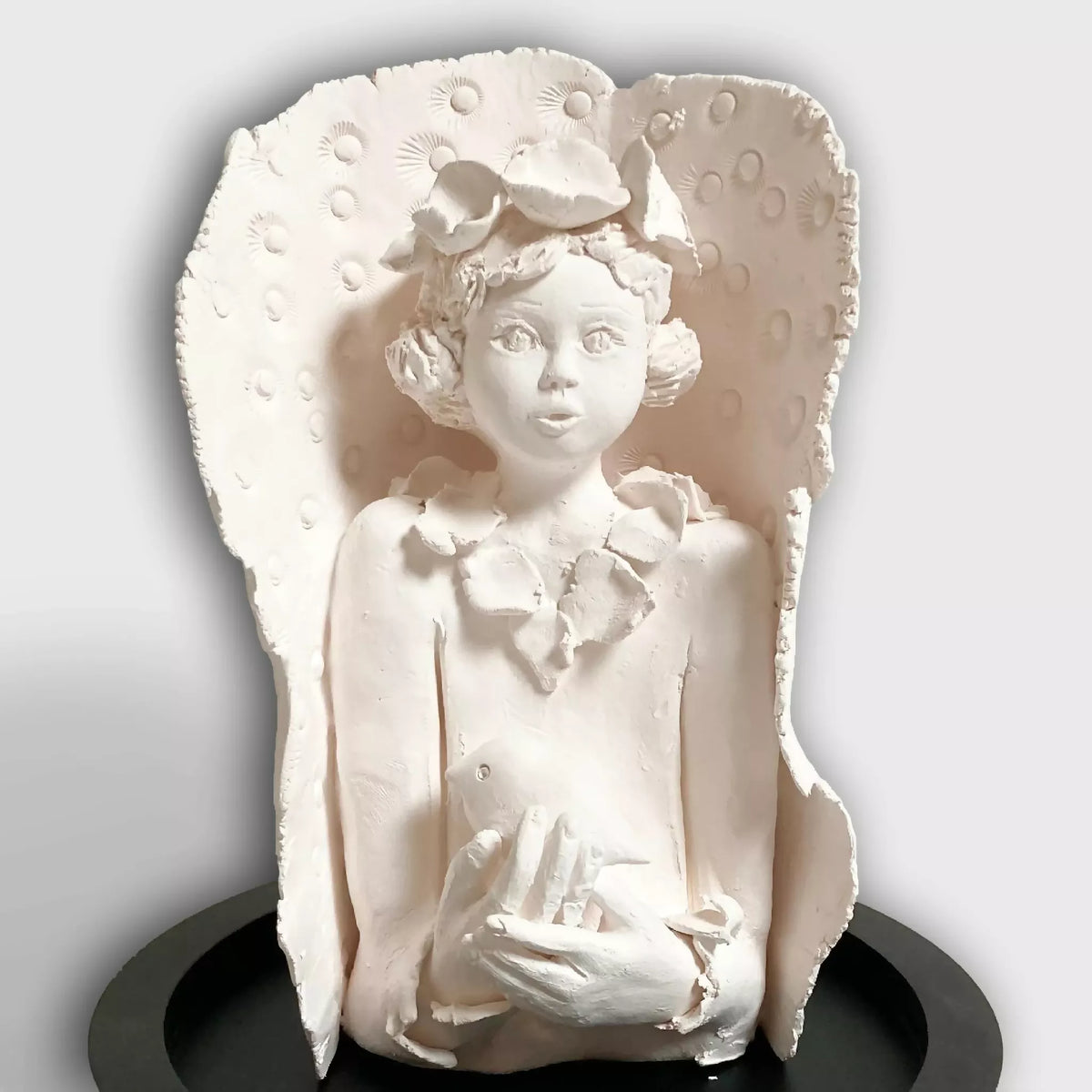 Sculpture femme à l’oiseau en relief, visage et mains tenant un petit oiseau, blanche