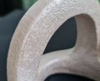 Détail sculpture en argile beige, surface granuleuse et ouverture en cercle