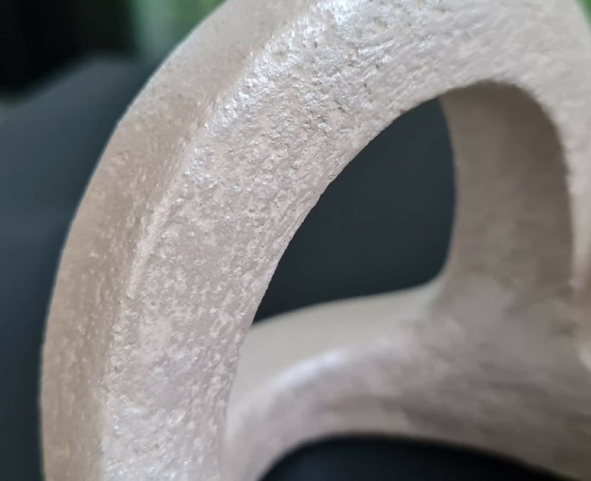 Détail sculpture en argile beige, surface granuleuse et ouverture en cercle