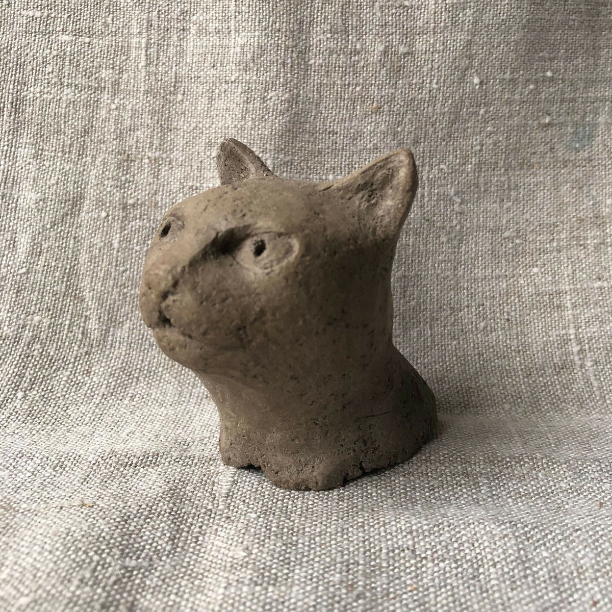 Petite sculpture en argile de chat, vue de trois-quarts, oreilles dressées.