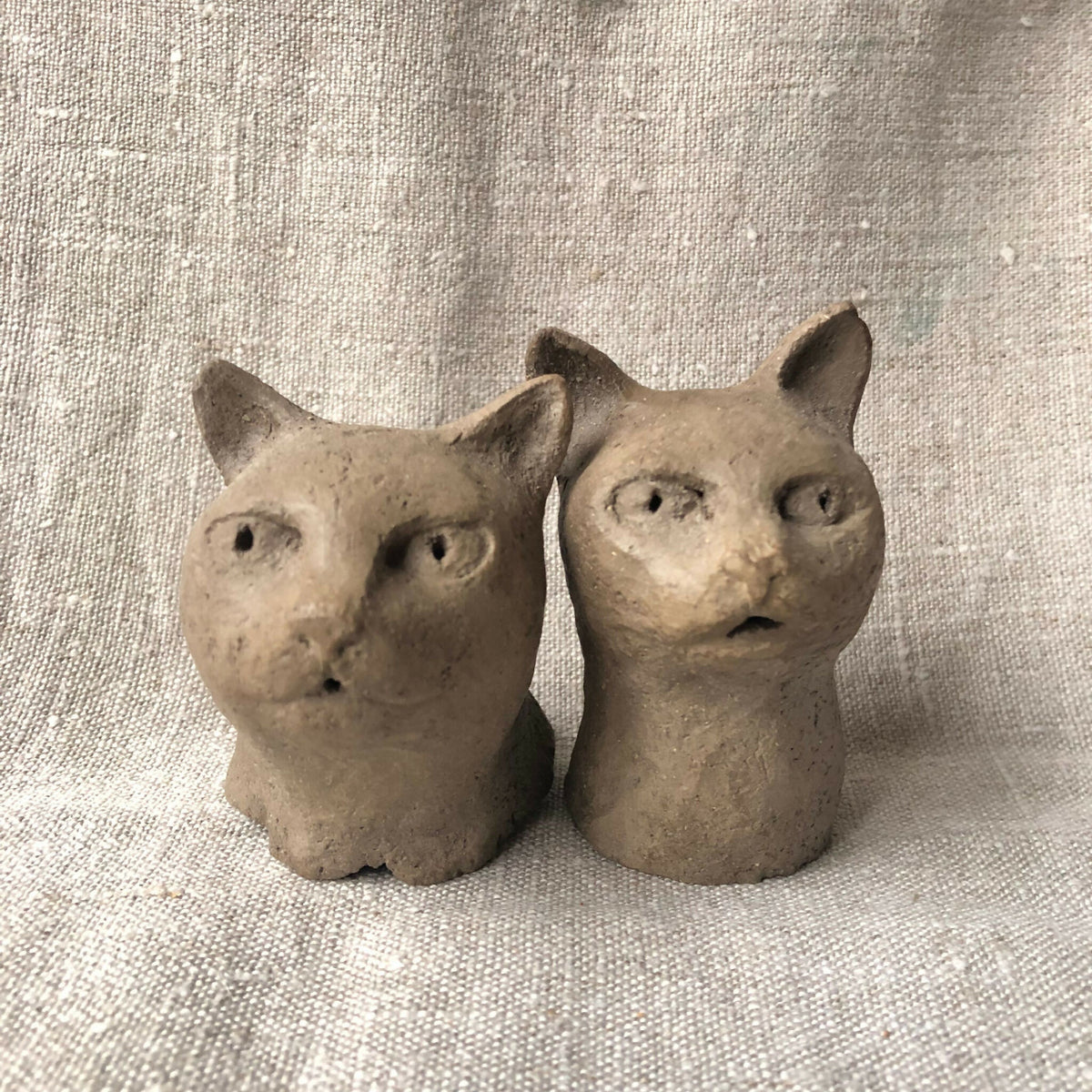 Paire de sculptures en argile de chats, deux petits félins assis côte à côte.