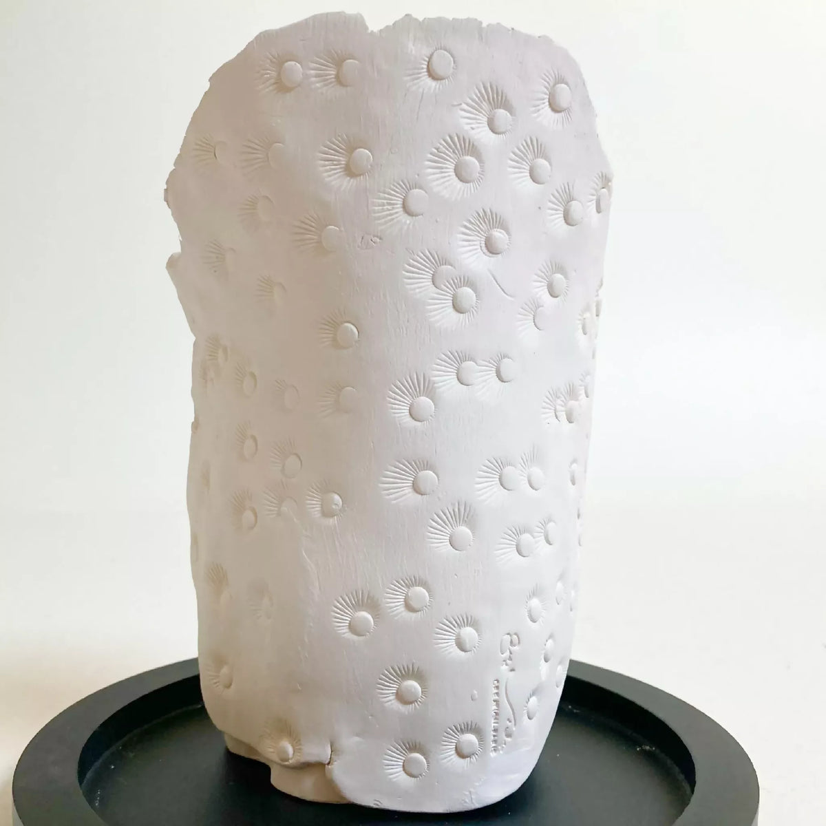 Sculpture d'enfant blanche vue arrière, fleurs en relief, sur base noire.