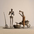 Sculpture décorative en métal, deux personnages mécaniques sur socle circulaire.