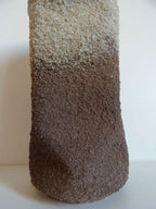 Sculpture cylindrique granuleuse, dégradé brun avec haut plus clair, forme compacte.