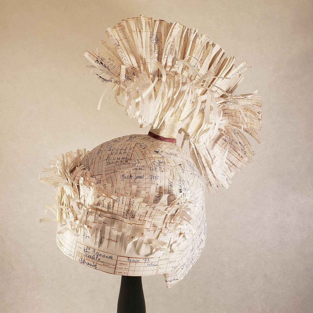 Casque à aigrette beige en papier imprimé, vue rapprochée de côté, plumet volumineux.
