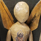 Poupée en papier beige avec ailes dorées, visage et peinture colorée sur la poitrine