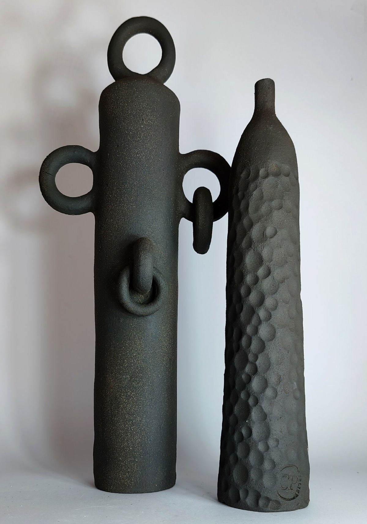 Paire de sculptures noir: totem à anneau supérieur et forme évasée texturée