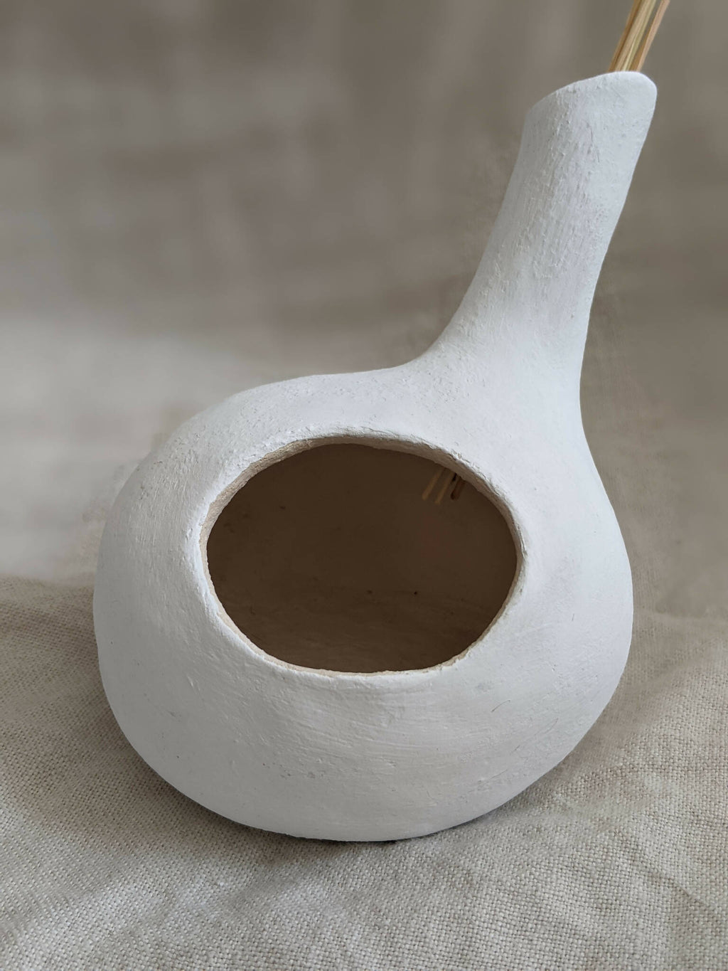 Vase sculpture bulbe blanc, ouverture circulaire avec quelques tiges