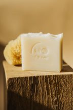 Savon shampooing solide Fauve ivoire, barre avec logo posée sur bois