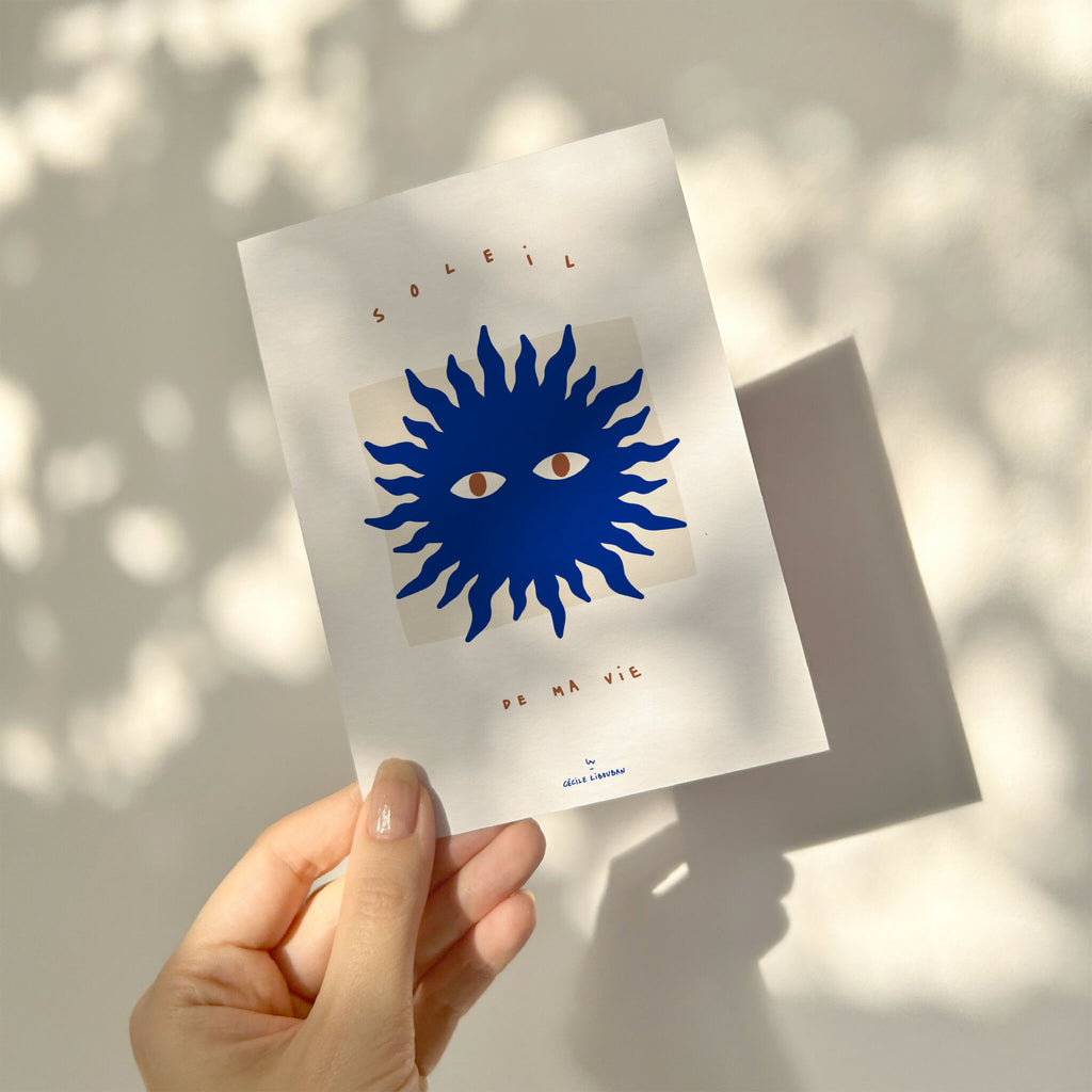 Carte à message blanche avec soleil bleu, visages et « de ma vie », tenue en main