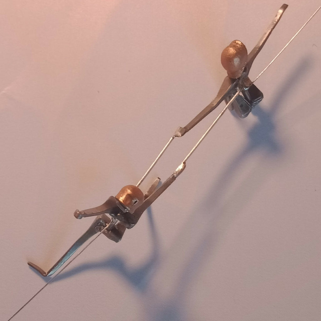 Figurines d’escrimeuses en acier, vue de dessus, têtes cuivre et posture en lunge.