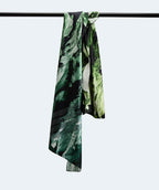 Écharpe en tissu fluide à motif vert et noir, drapée sur une barre