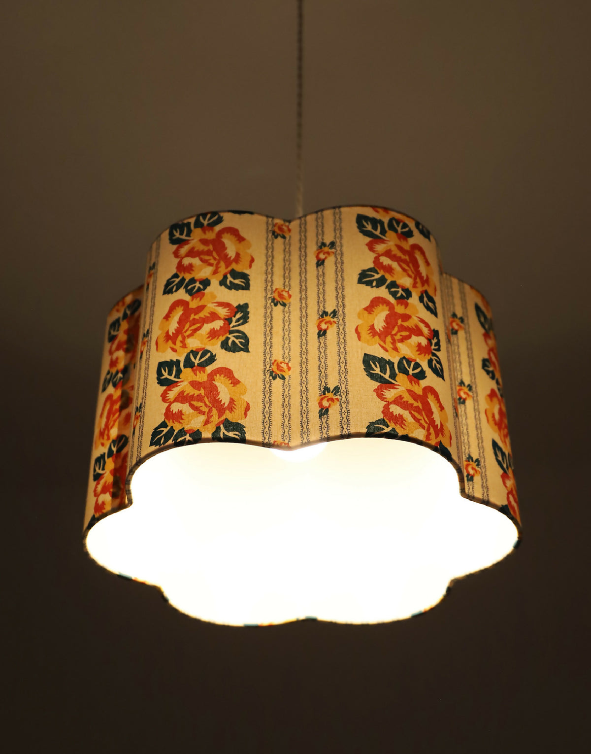 Abat-jour forme fleur en tissu crème à fleurs orange, lumière diffusée vers le bas.