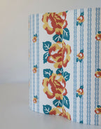 Abat-jour forme fleur en tissu bleu, grandes fleurs orange et feuillages vert foncé.