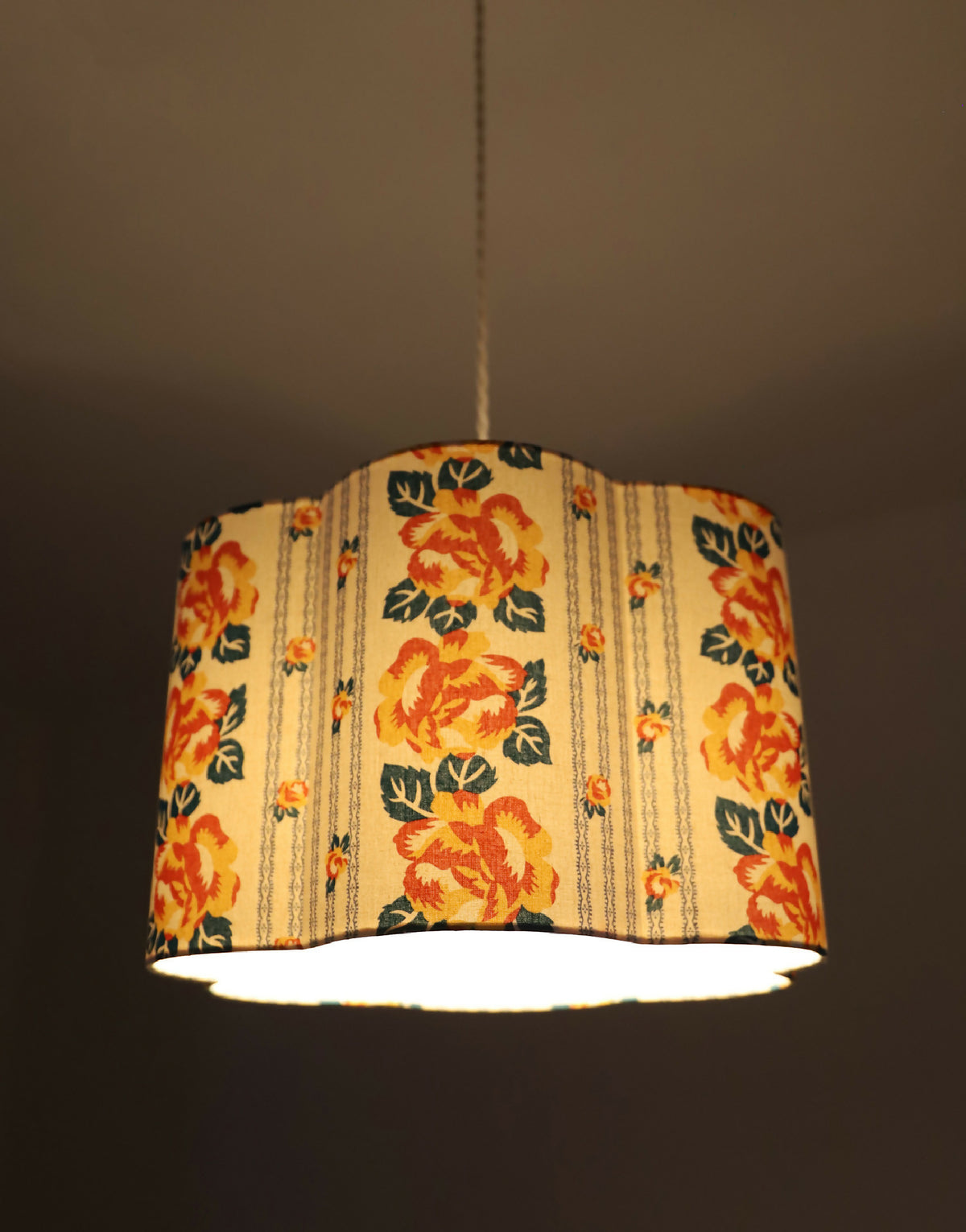 Abat-jour forme fleur en tissu crème à fleurs orange, motif rayé de chaînettes.