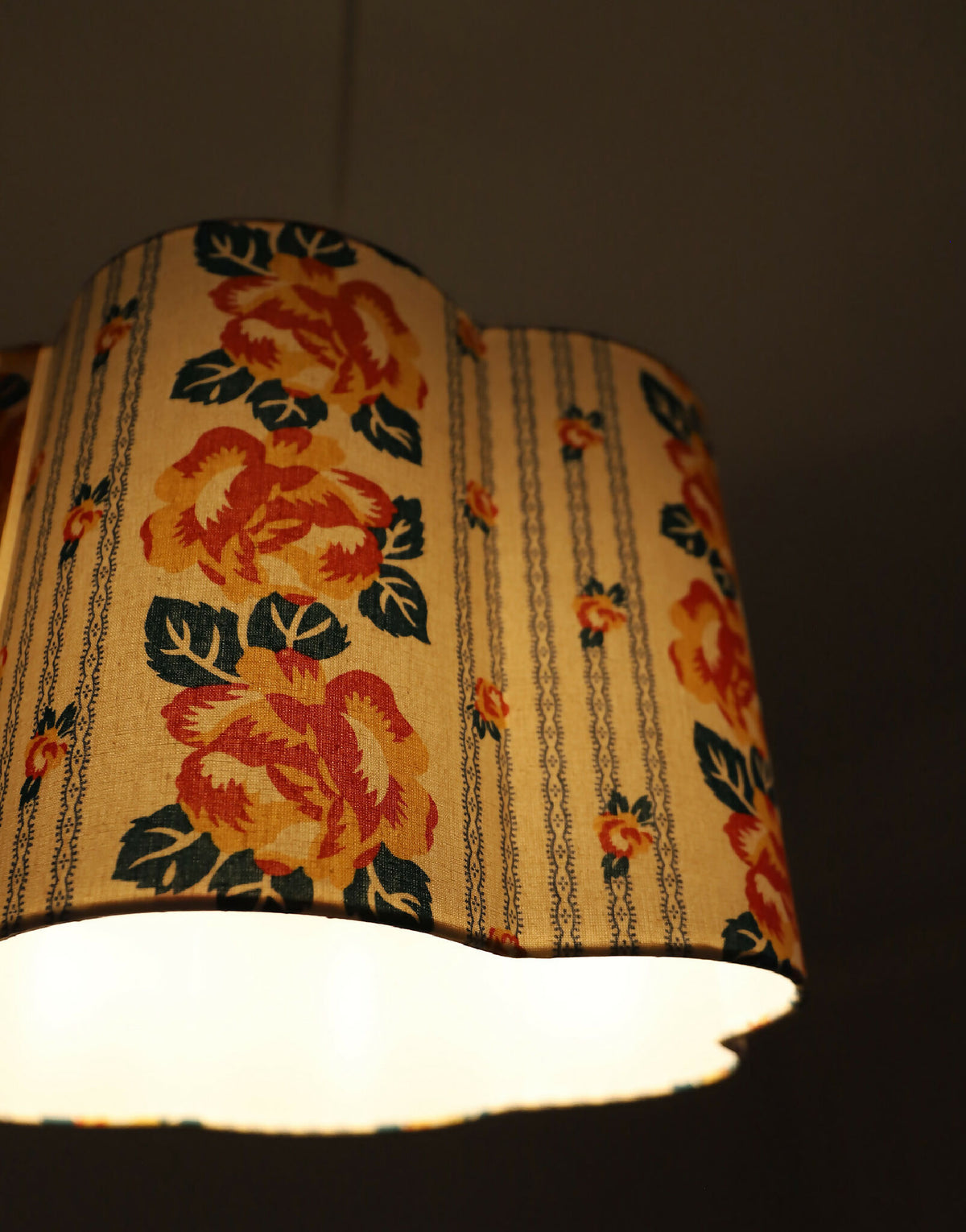 Abat-jour forme fleur en tissu crème, grandes fleurs orange, décor floral et chaînettes.