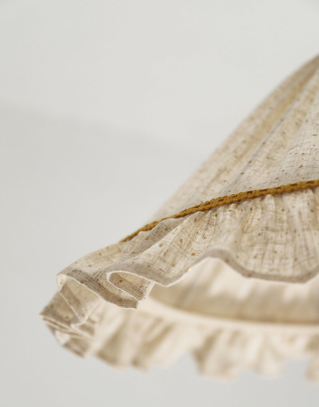 Détail du volant de l’abat-jour conique en lin et coton beige avec liseré doré