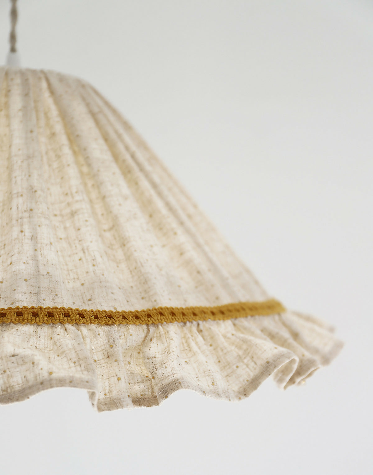 Détail de l’ourlet du volant de l’abat-jour conique en lin et coton beige