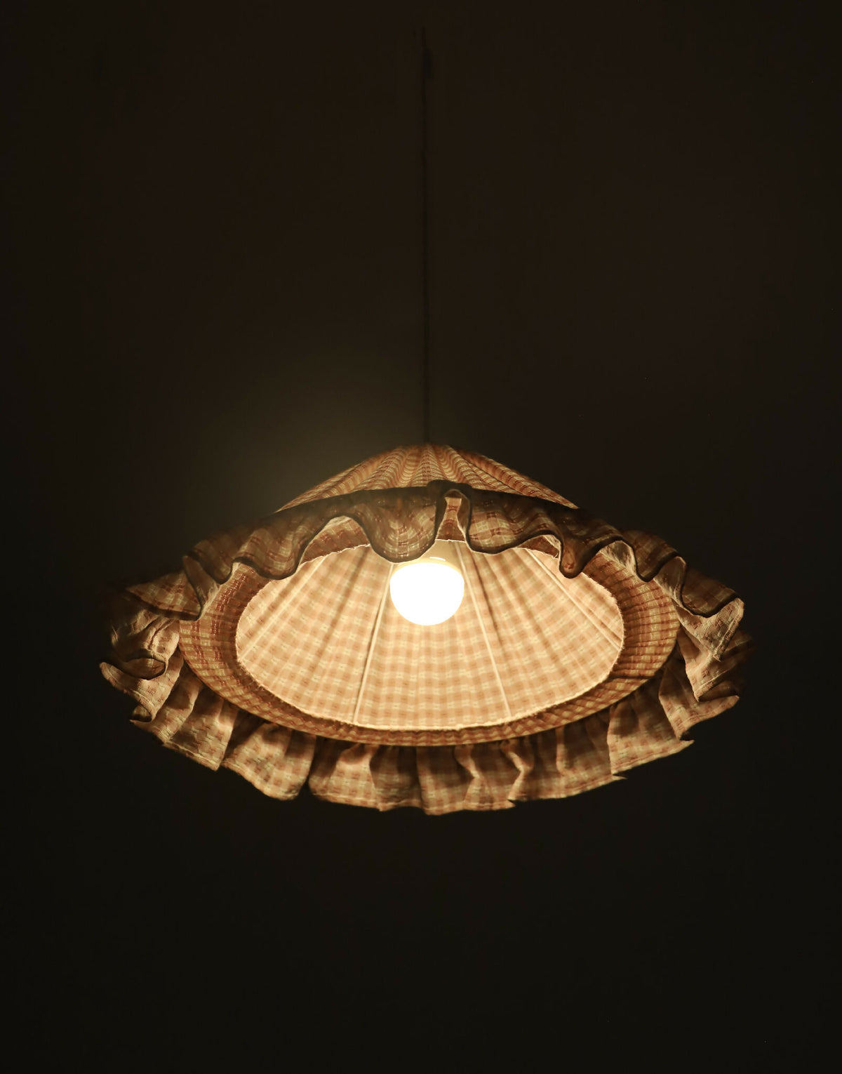 Suspension conique à petits carreaux, volant froncé et ouverture centrale pour la lampe.