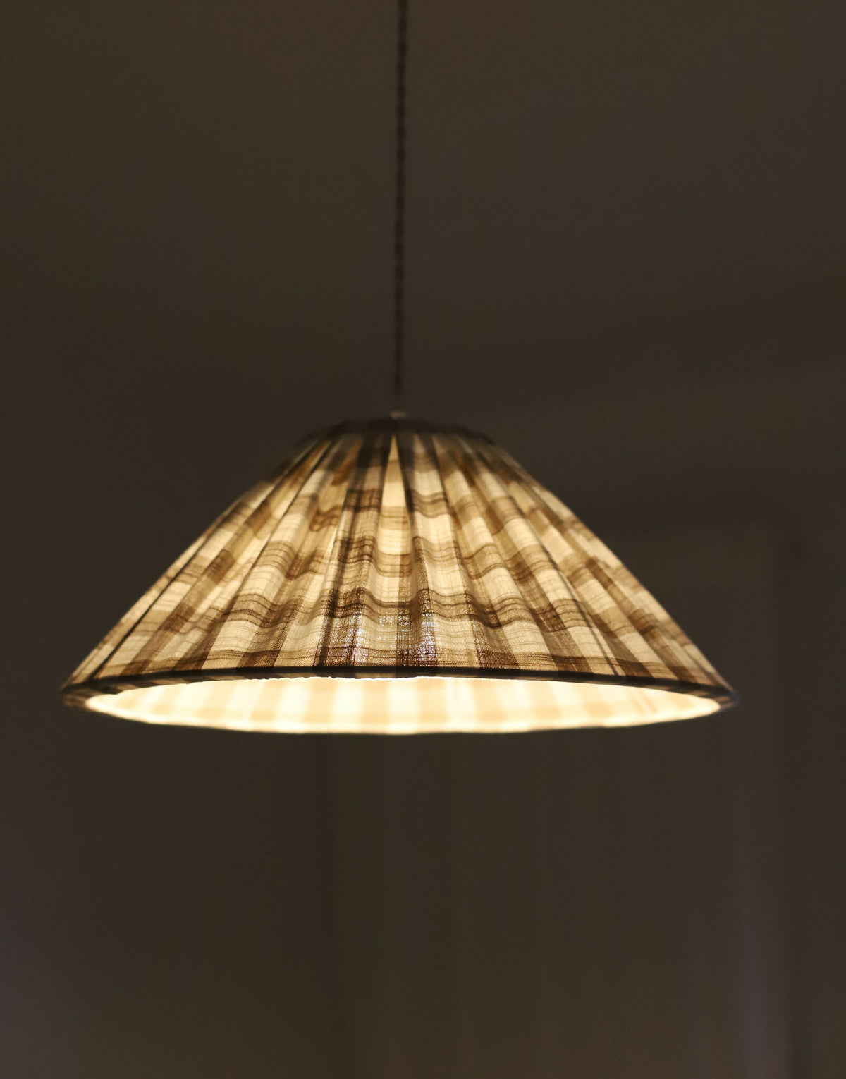Suspension conique en coton vichy beige avec lumière chaude à travers l’abat-jour