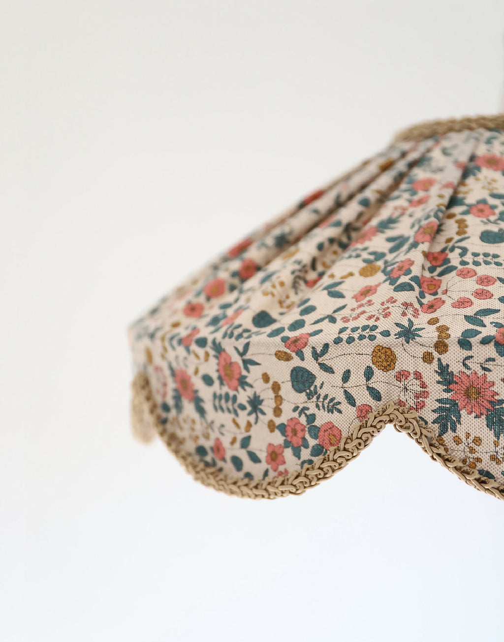 Détail du bord festonné de l’abat-jour en tissu floral, finition en dentelle beige.