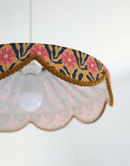 Détail de la bordure de l’abat-jour : tresse dorée et tissu floral à fleurs roses.