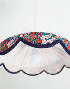 Abat-jour festonné floral mille fleurs avec bord bleu marine et motif multicolore.