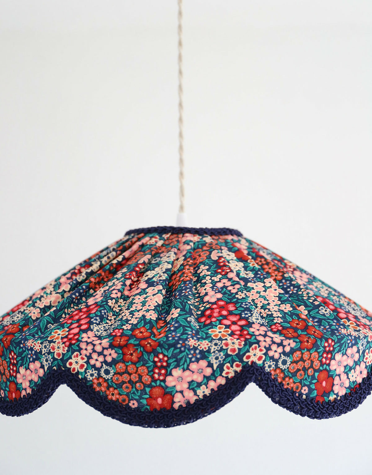 Suspension abat-jour floral mille fleurs, tissu coloré avec bord festonné bleu marine.