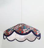 Abat-jour suspendu festonné en tissu floral mille fleurs, base blanche et bord bleu marine.