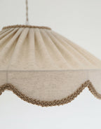 Abat-jour suspendu en tissu beige, détail de bordure festonnée en tresse
